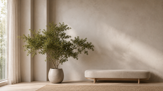 Faux greenery with wide organic foliage placed beside a low bench creating calm visual flow in a minimal interior.