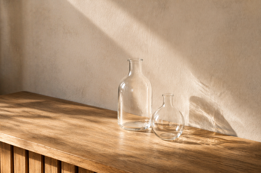 Two transparent glass accents placed with spacing on a wooden table, creating balanced hierarchy through light and shadow.