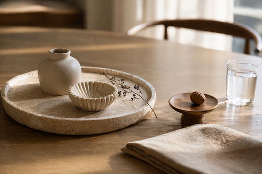 Minimal table with a ceramic object and wood accent placed with spacing.