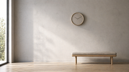 Minimal wall with a subtle round clock placed slightly off-center above a low bench, guiding visual attention flow through balanced spacing and soft natural light.