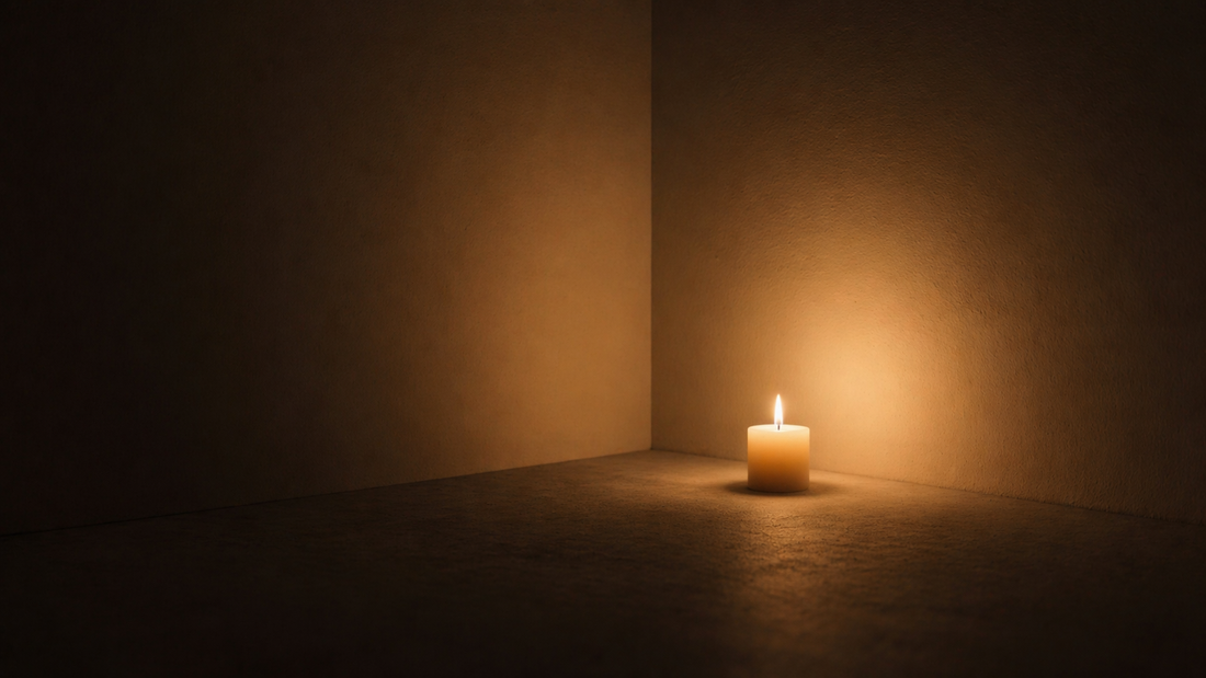 Minimal room with a single candle casting soft uneven light creating a warm emotional tone.
